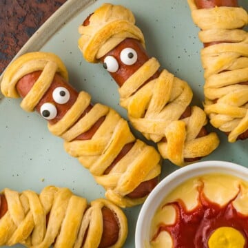 Mummy dogs with candy eyes on a plate.