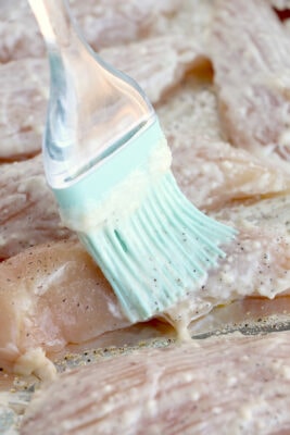 Brushing half of the mixture onto the chicken tenders.