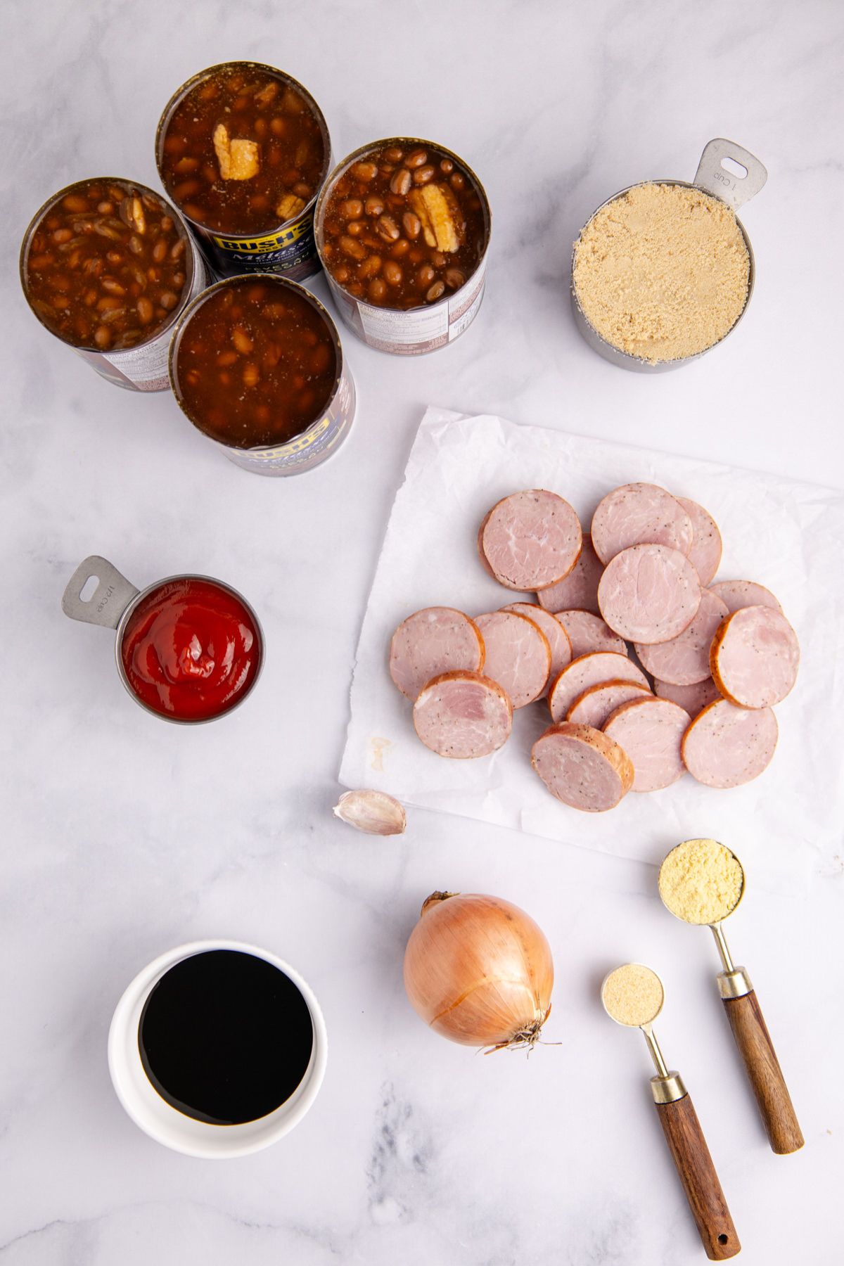 Ingredients for baked beans with sausage on a table.