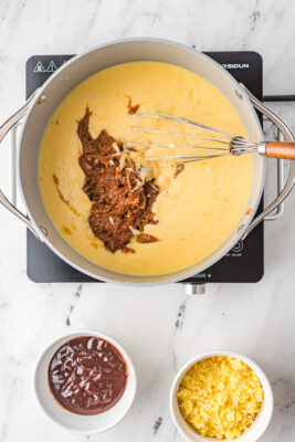 Adding meat to melted cheese inside a pot.