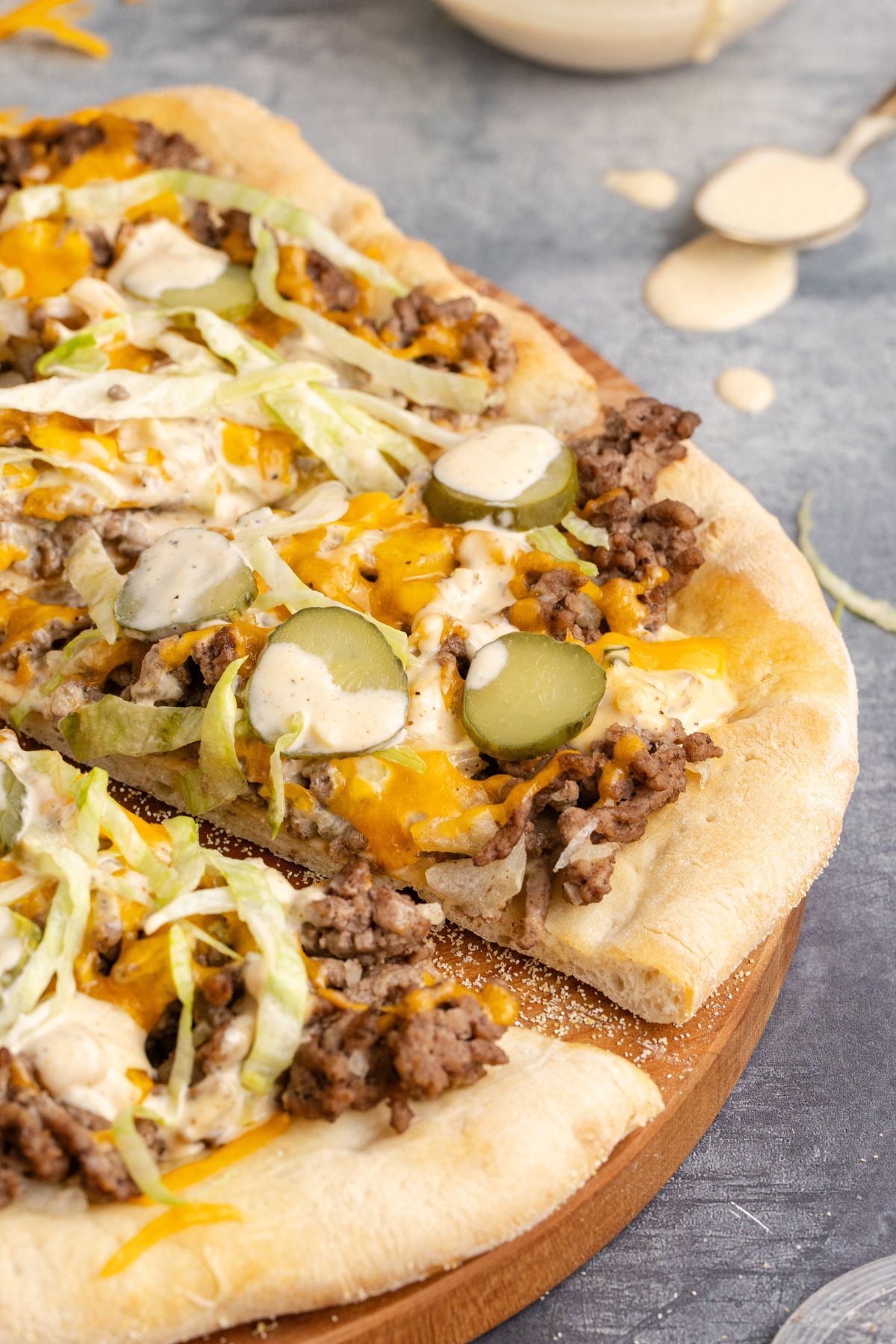 Big mac pizza with ground beef, cheese, lettuce and pickles on it.