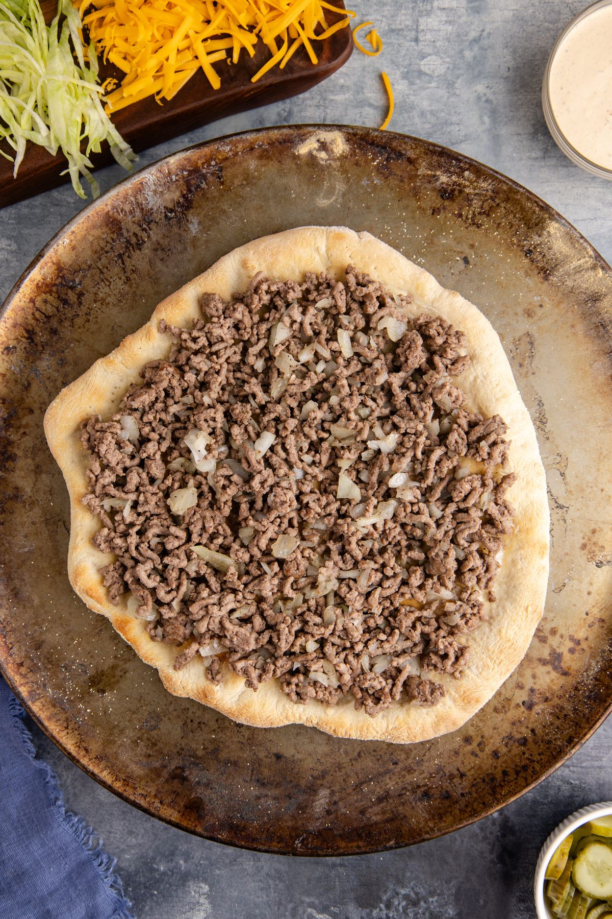 Beef mixture added to the pizza crust.