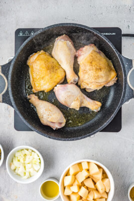 Chicken cooking in a large skillet.