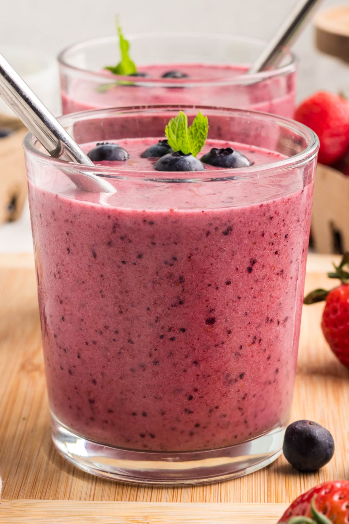 Berry smoothie with metal straw and blueberries inside.