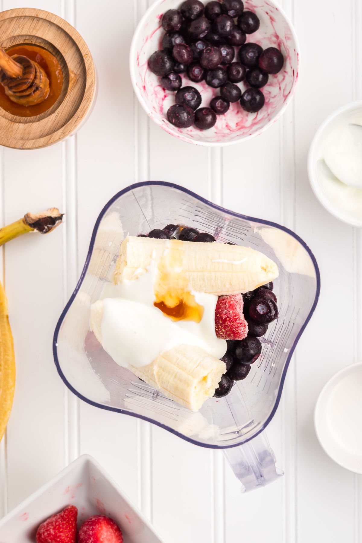 Fruit, yogurt, milk, and honey in a blender.