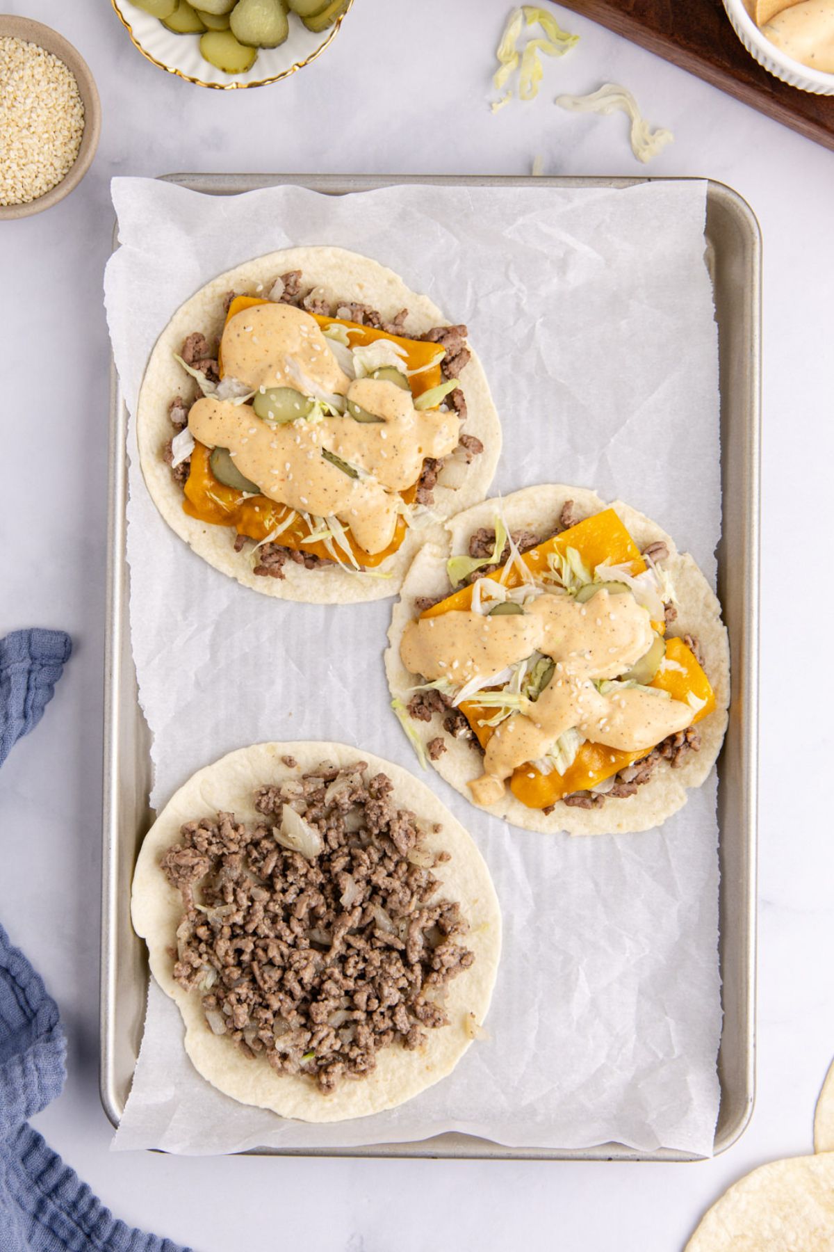 Beef mixture with the filling ingredients into three tacos on a sheet pan.