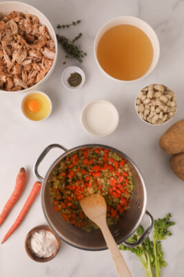Onion, carrots, celery, salt, and pepper cooking in a large sauce pan.
