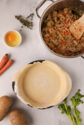 Dough lined pie plate placed next to the sauce pan.