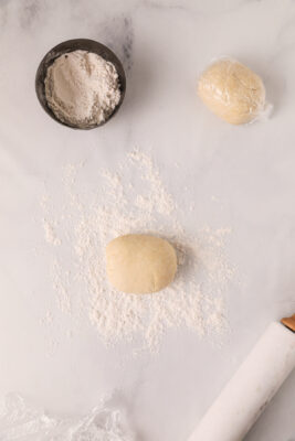 Chilled dough placed on the counter with flour and a rolling pin.