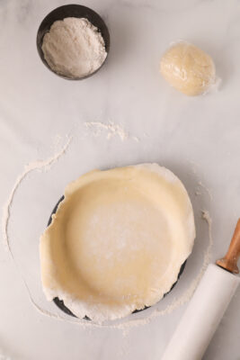 Rolled dough placed inside a pie dish.
