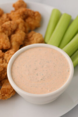 Buffalo ranch sauce on the plate with chicken nuggets and celery sticks.