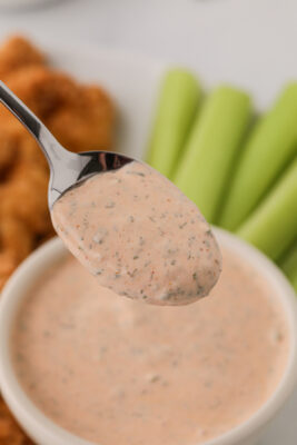 A spoon lifting out some of the buffalo ranch sauce from the bowl.