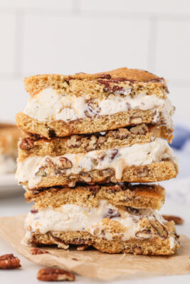 Stack of three ice cream cookie sandwiches on a wooden cutting board.