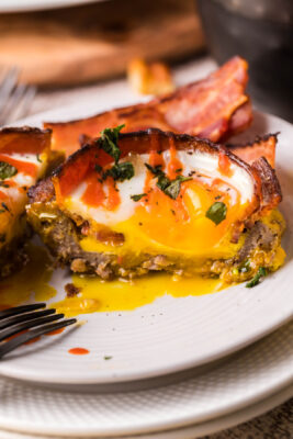 half eaten keto bacon egg cup on a white plate.