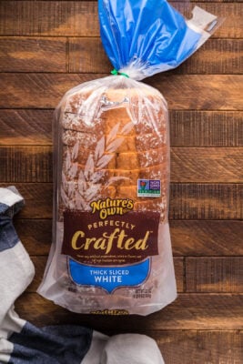 Packaged loaf of thick sliced bread on a wooden table.