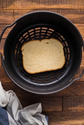Thick slice of bread placed inside an air fryer basket.