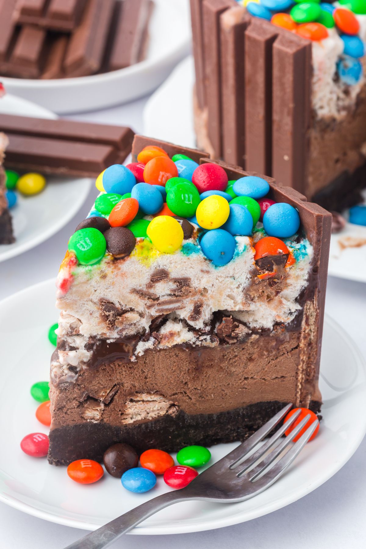 Kit kat ice cream cake with m&ms on top of a plate with a fork.