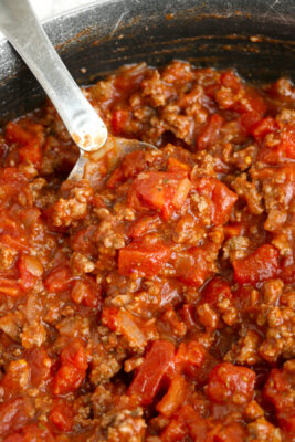 Prepared school cafeteria spaghetti sauce in a skillet with a metal spoon.