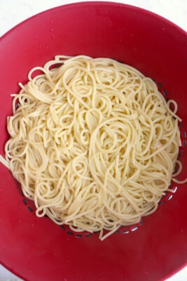 Cooked spaghetti noodles in a strainer.