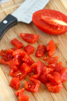 Fresh tomatoes diced on a wooden cutting board.