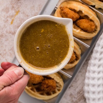 Mustard maple syrup hovering over some chicken waffle tacos.