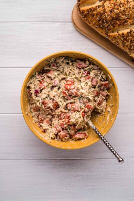 Overhead photo of a yellow bowl with Tomato Bruschetta, cheese, mayonnaise and pepper. The ingredients have been mixed.