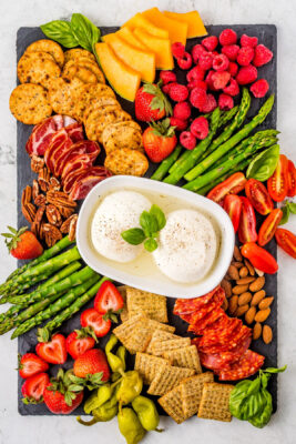More ingredients placed onto the board surrounding the Burrata cheese.