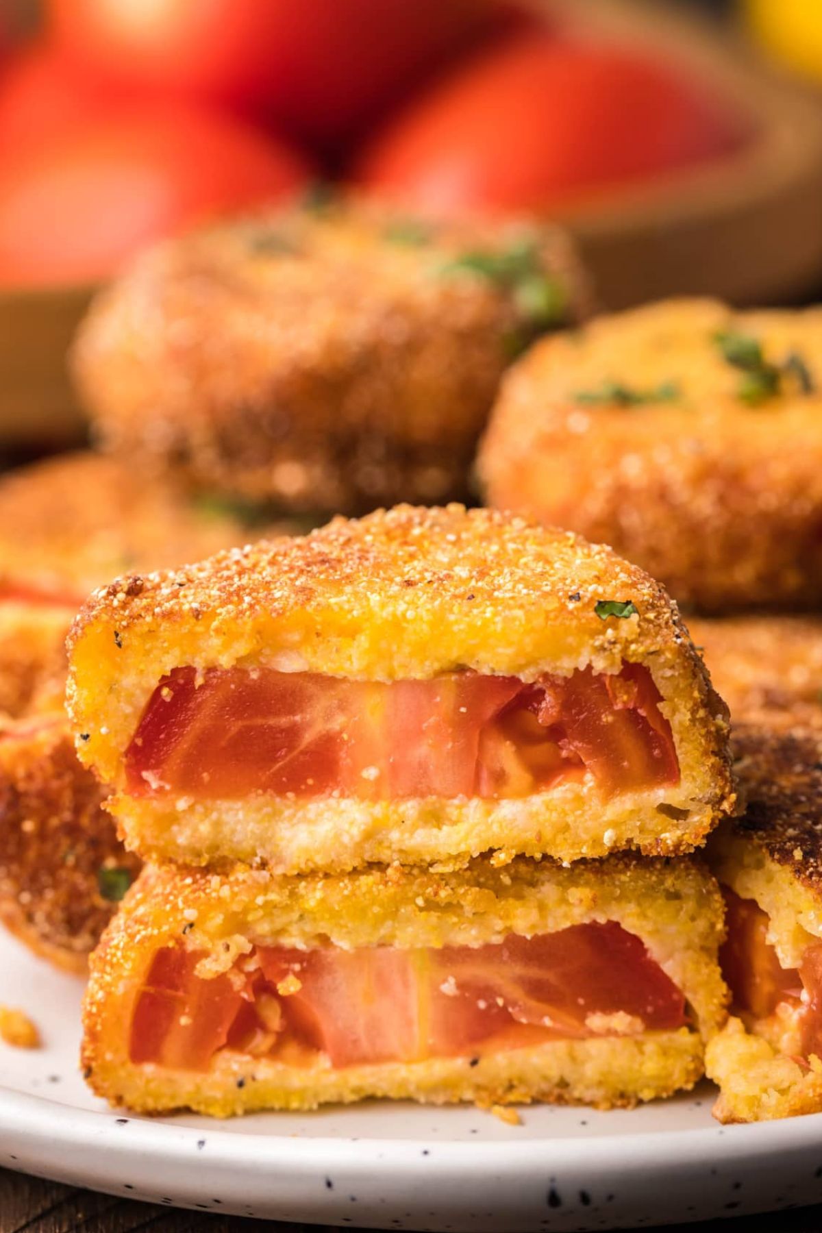A fried tomato, coated in breading and cut it half stacked on top of one other.