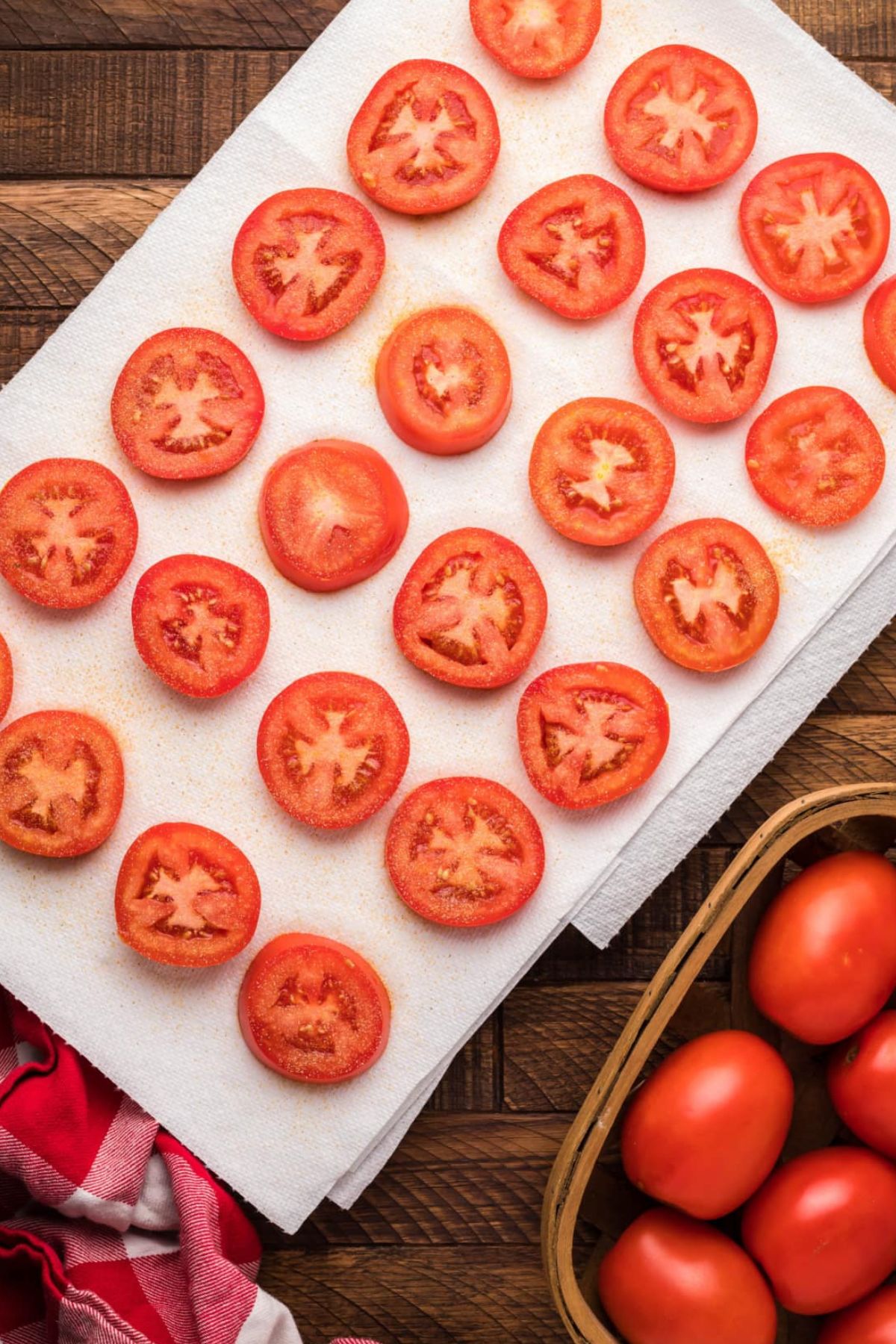 Tomato slices lay out on a paper towel.