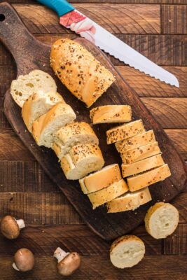 Baguette bread sliced on a cutting board with a bread knife.