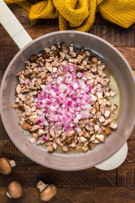 Onions added to mushrooms in the skillet.