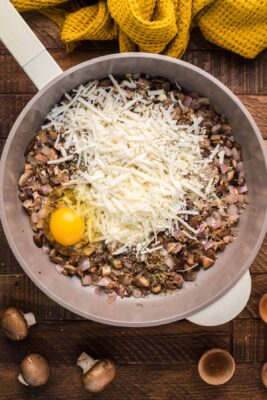 Egg added with cheeses to mushrooms in the skillet.