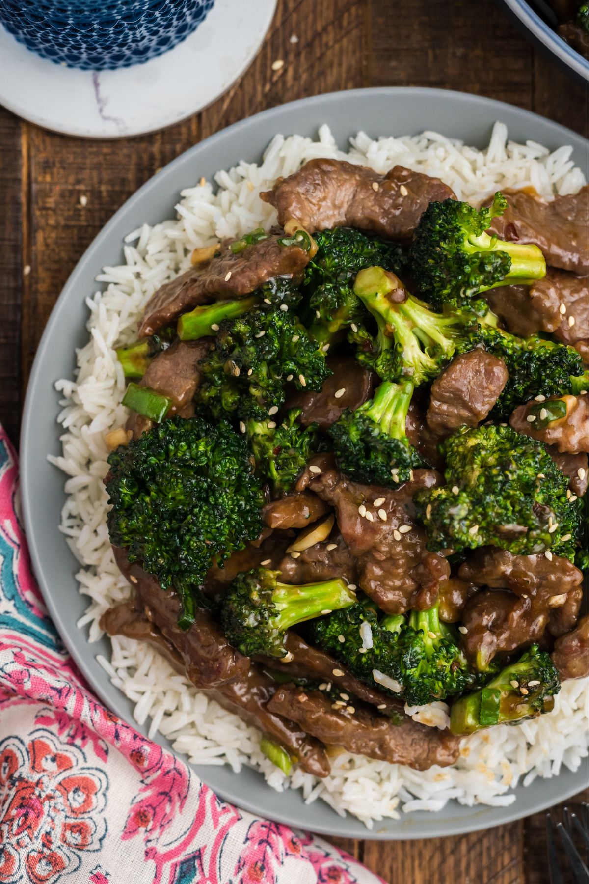 A full plate of white rice with beef, broccoli and sesame seeds.