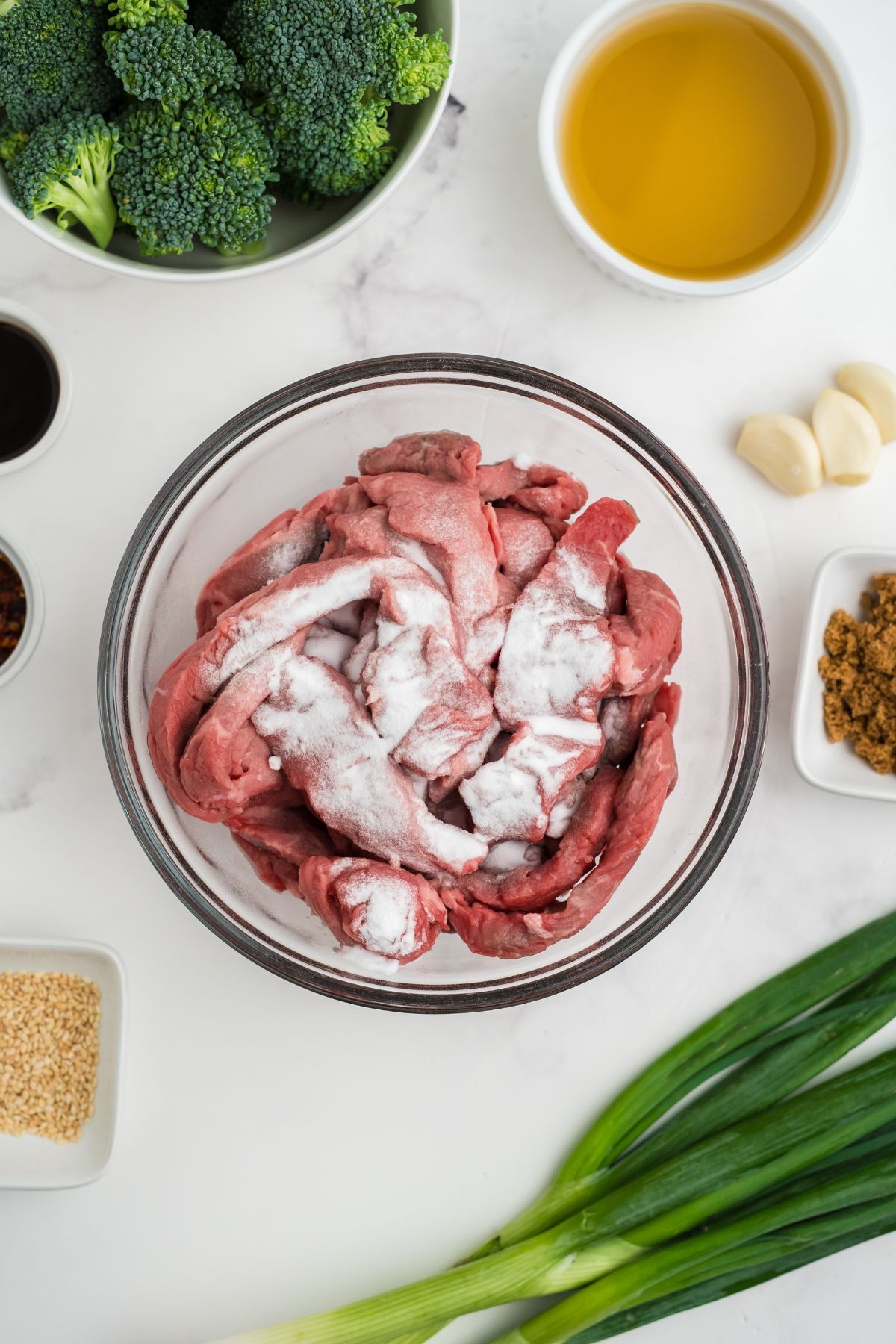 Flank steak in a bowl with baking soda on top.