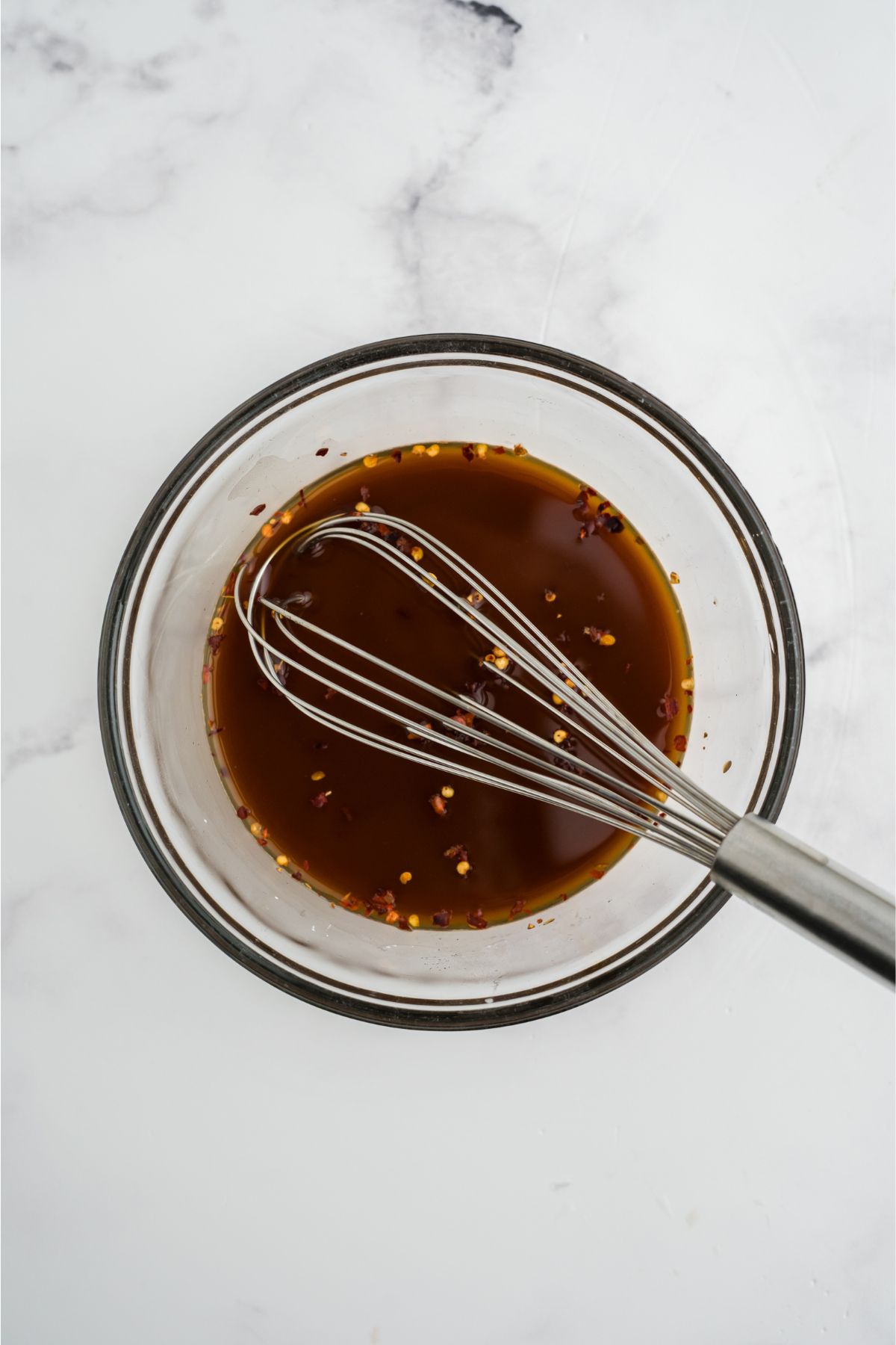 Sauce ingredients mixed in a bowl with a whisk resting in the bowl.