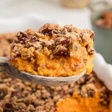 A spoonful of candied sweet potato casserole held in the air.