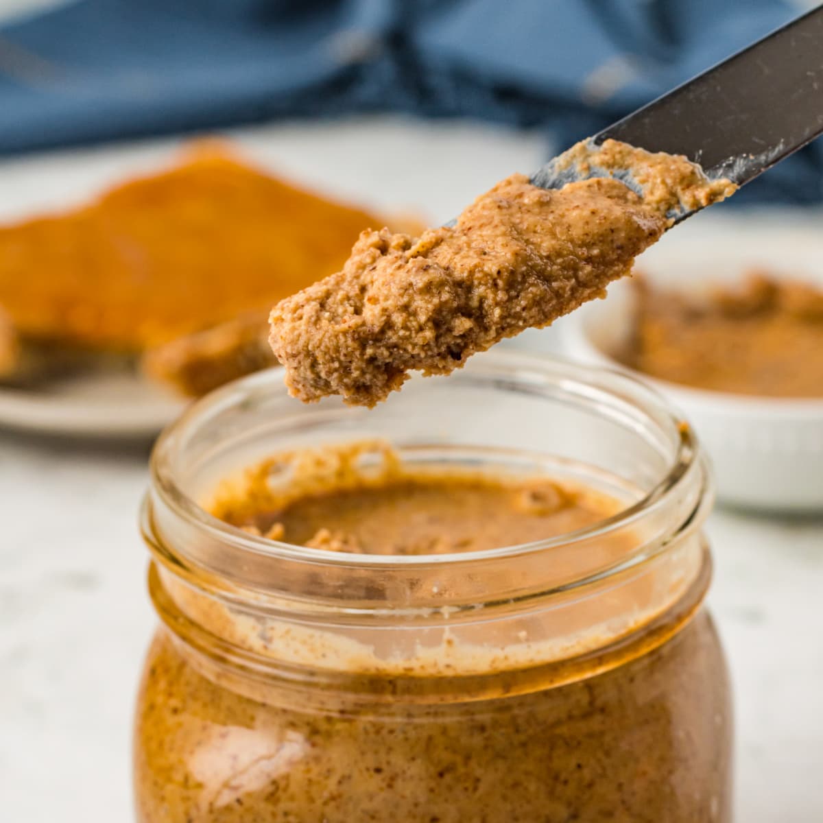 Mason jar of Organic Almond Butter on a butter knife 