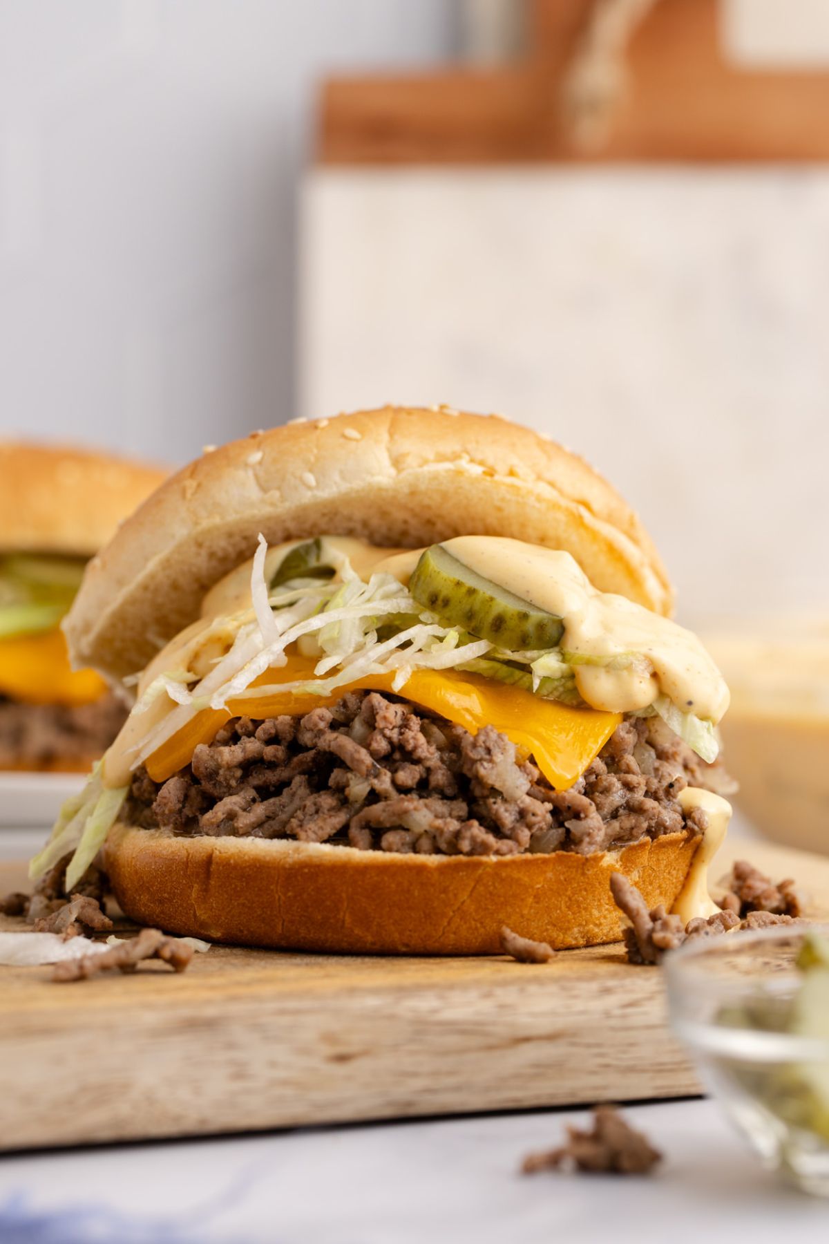 Slice of cheese on the bottom bun, then top it with the meat, Mac sauce, lettuce, and pickles.