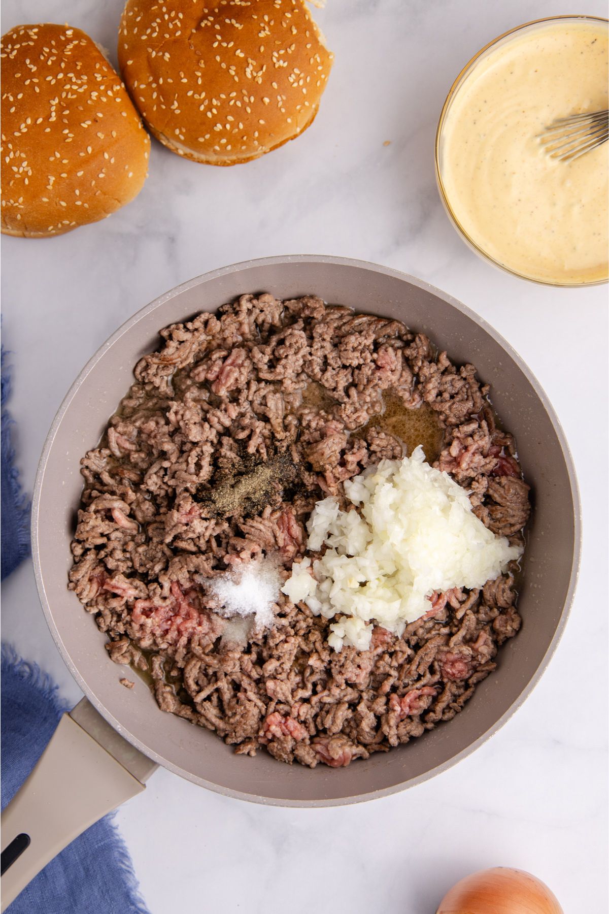 Ground beef and onions cooking in a skillet.