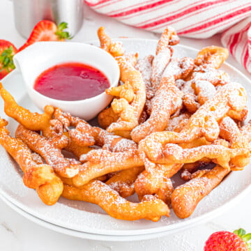 Funnel cake fries on a plate with strawberry sauce to dip.