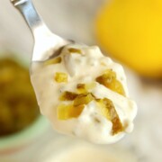 A spoon holding some 3 ingredient tartar sauce with speckles of relish on top.