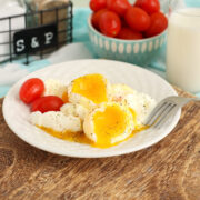 A plate of air fryer soft boiled eggs on a plate with a bowl of tomatoes in the background.