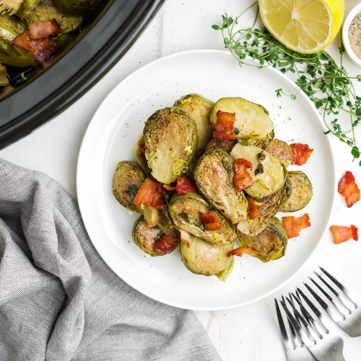 Plate full of Slow Cooker Brussels Sprouts with lemon wedge beside plate and forks