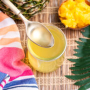 Pineapple syrup in a jar with a spoon up over the jar.