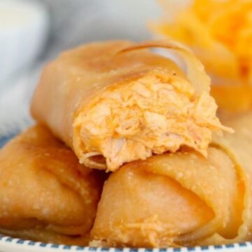 Close-up of a plate with buffalo chicken rolls, showing the shredded chicken stuffing visible in a cut piece.