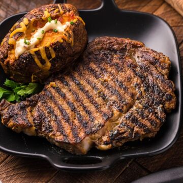 Grilled steak and a loaded baked potato on plate.