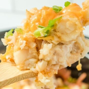 A wooden fork lifting a portion of casserole garnished with chopped green onions, focused against a blurred background, ready to prepare in just 10 minutes.