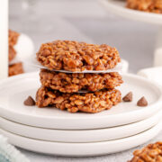 A stack of star crunch cookies on a stack of white plates with more around on the table.