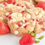 A pile of strawberry cookies garnished with fresh strawberries.