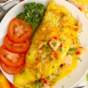 A plate with a salmon omelet, tomato slices, and fresh parsley.